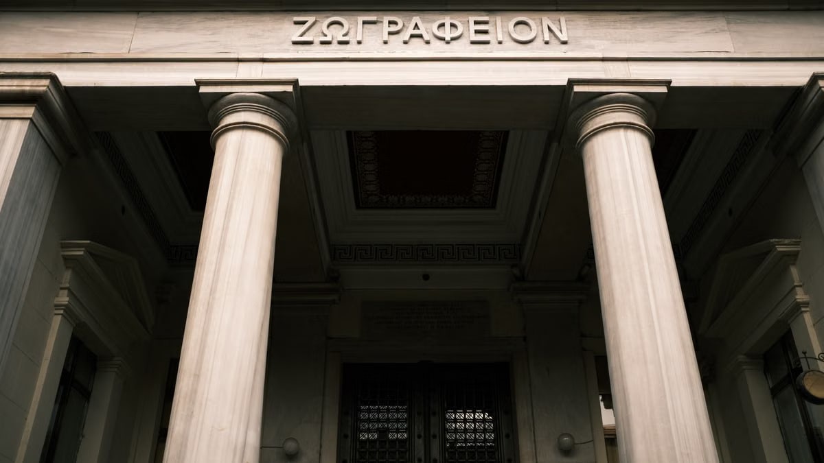 Low angle view of a historical building facade with Greek columns and inscriptions.